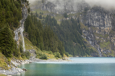 在瑞士伯尔尼斯奥伯兰高山的奥斯金森西 Oeschinen湖草地松树雪山地方风景湖岸表面全景晴天瀑布图片