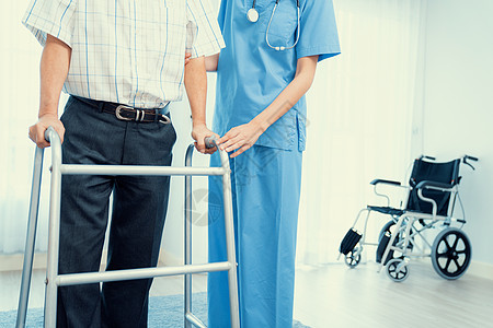理疗师协助她满足的高级病人用折叠行走器退休医生医院疗养医学物理老年男人卫生康复图片