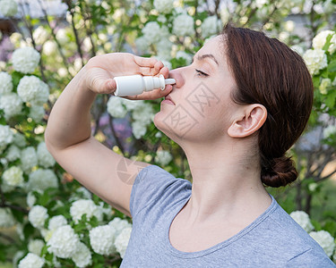 白种女人在公园散步时用鼻涕喷雾卫生喷嚏疾病治疗支气管鼻音女性流感药品瓶子图片