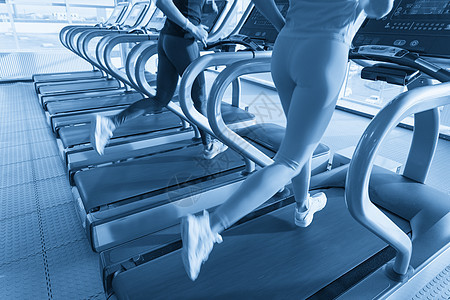 两名年轻妇女在健身运动场上跑步机器赛跑者中心喜悦蓝色运动装成人运动火车健身房图片