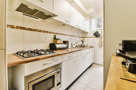 一个有白柜子和炉灶顶炉的厨房住宅房间器具财产建筑学奢华公寓装饰烹饪地面图片