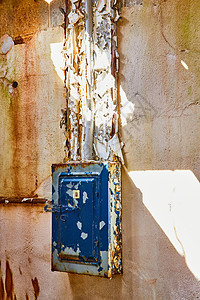 被废弃的石膏墙壁 在太阳日落带蓝色剥皮涂漆的电箱图片