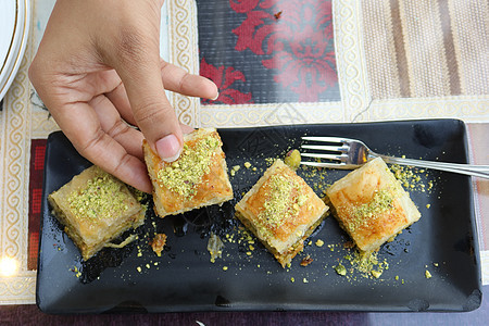 一个盘子上的阿拉伯甜甜点坚果美食食物糕点糖浆金子榛子文化小吃棕色图片
