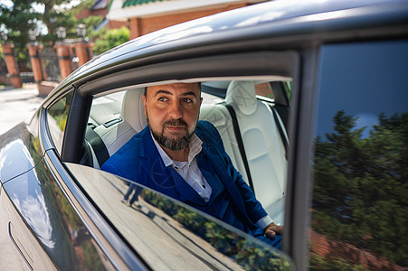 一个穿蓝色西装的天主教男子坐在汽车后座时 望着窗外的开阔处 公务舱乘客窗户工作管理人员运输沙龙车轮套装生意金融沉思图片