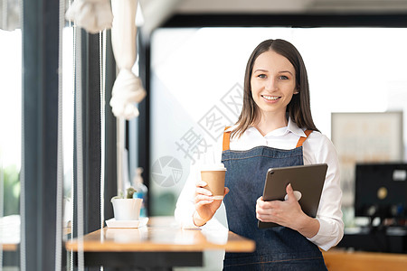 开一家小企业 一个穿着围裙的快乐亚洲女人站在酒吧柜台咖啡店附近 小企业主 餐厅 咖啡师 咖啡馆 在线 中小企业 企业家和卖家概念图片
