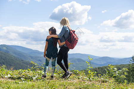 母亲和女儿在山上登山后享受风景图片