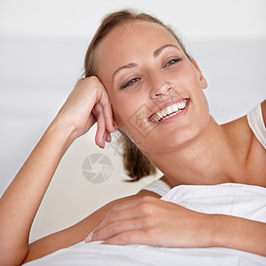 有个美丽的年轻女人在床上放松时微笑着笑容 她很可爱图片
