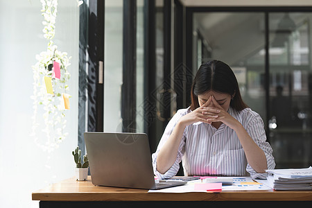 亚洲女性在笔记本电脑上工作时压力很大 疲惫的亚洲女商务人士在办公室头痛 工作时感觉不舒服经理挑战沙发金融情感失败医生悲伤员工创造图片