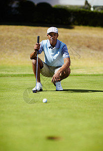 高尔夫球手蹲在绿色上 盯着一个小矮人图片
