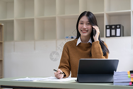肖像年轻的亚洲女商务人士美丽迷人微笑着在办公室里用手机说话呼唤公司工作女性笔记本商业商务女士经理技术图片