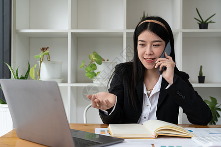 年轻的办公室亚裔女性一边用手机与某人交谈 一边用快乐的面部表情眺望远方图片