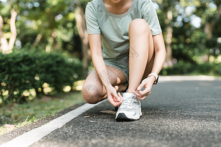 女性系鞋带 特写健身选手准备在户外慢跑的女性运动赛跑者活动训练跑步成人公园运动女孩蕾丝鞋类女士图片