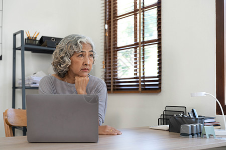 年长的亚洲妇女坐在家中 她有压力和生病 退休概念 老年健康保险 第12条金融成人桌子技术公民商业会计女士财政账单图片