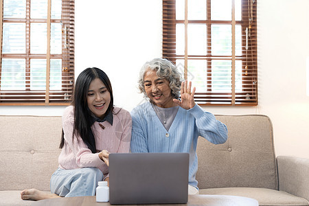 微笑的年长母亲和成年女儿一起使用电话 坐在家里舒适的沙发上 快乐的年轻女人和成熟的妈妈看着智能手机屏幕 看视频 玩得开心 两代人图片