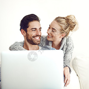 充分利用我们的在线时间 一对年轻夫妇在家里的沙发上使用笔记本电脑图片