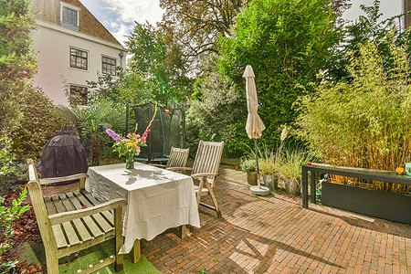 后院 有一张桌椅和一栋房子花朵建筑学建筑住宅窗户花园家具石头雨伞奢华图片