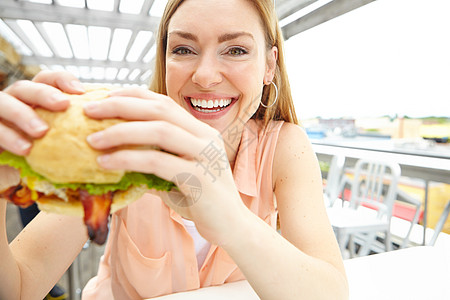 这看起来很好吃 一个漂亮的年轻女人的肖像 在餐厅里吃一大块美味的汉堡包图片