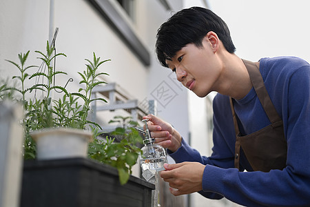 穿着围裙的无照顾的亚洲男子在后院照看植物 