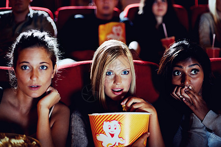 他们真的很喜欢这部电影 三个女朋友坐在一起 在电影院里看起来既害怕又紧张图片