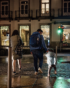 父亲握着小女儿的手 家人晚上带着绿灯在路上过夜;孩子和家人图片