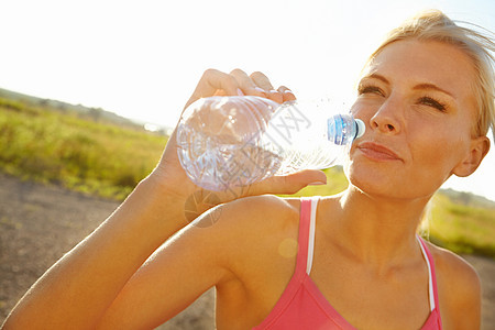 休息享受风景 一个穿着运动服的年轻美女 从瓶子里拿饮用水来喝吧图片