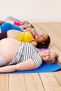 孕妇瑜伽进行呼吸锻炼 一群孕妇躺在运动垫子上躺着——肖像画;以及一些怀孕妇女背景