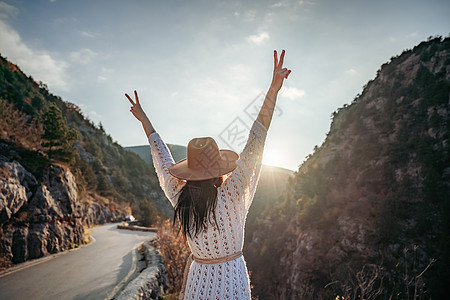 穿着棕帽子和白色毛衣的女旅行者 看着惊人的山峰和森林 漫游概念 大气史诗时刻晴天远足旅行女性潮人冒险探索假期旅游背包图片