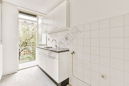 一个有水槽和窗户的白色厨房墙壁瓷砖装饰器具木头建筑学房子财产龙头内阁图片