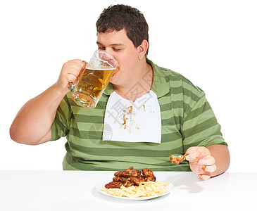 鸡翅薯条胖子吃东西 一个肥胖的年轻男人 穿着小披肩喝啤酒 在他面前放着一盘鸡翅和薯条背景