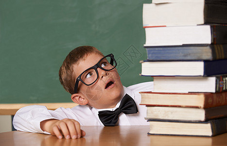 说学校很简单 一个男孩戴眼镜和领结 看一大堆书的年轻男孩儿也很容易图片