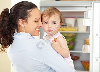 可爱的婴儿在开着的冰箱前 被爱护妈妈抱住 她有那么大顾小题大做?图片