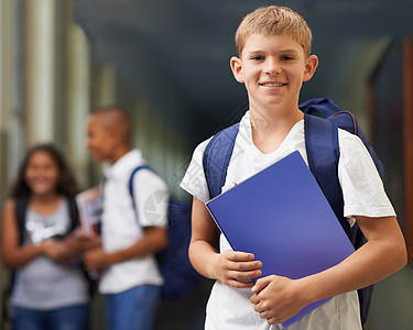 他是一个勤奋的学生 一个快乐的男生站在走廊里 背景是他的朋友图片