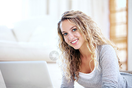 在全球网络上自由统治 一个年轻漂亮的女人躺在地板上 用笔记本电脑浏览互联网图片