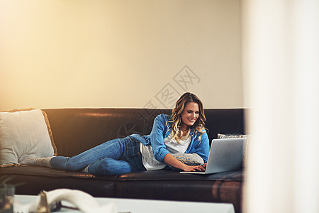 当您放松时 生活会轻松得多 一个放松的年轻女人在家里的沙发上使用笔记本电脑图片