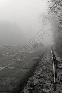 汽车在雾蒙蒙的路上行驶 车头灯或前灯亮着 低能见度冬季恶劣天气下危险驾驶汽车森林速度季节交通大灯薄雾旅行运输街道车辆图片