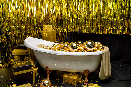 充满金球的浴缸 盛装着节日金球的闪亮古老浴室 新年 圣诞洗手间室内住宅地面大理石坐浴小屋大厦财产公寓龙头房子图片