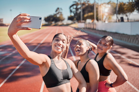 女跑步者团体在跑道上进行健身 交友和自拍 以进行训练 锻炼和有氧运动 运动 电话和女队在体育场锻炼后微笑 放松并摆姿势拍照图片