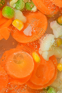 特写镜头新鲜的汤蔬菜用红萝卜 豌豆 花椰菜和玉米在白色背景 在白色背景的沸水中用胡萝卜 豌豆 花椰菜和玉米汤蔬菜 特写 垂直图像图片