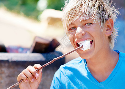完美的露营甜食 一个小男孩在棍子上吃棉花糖的景象成人男性孩子青年手指戒指孩子们工作室童年男生图片
