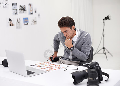 一位年轻的摄影师坐在桌子上的编辑图象上 在寻找封面图像背景图片