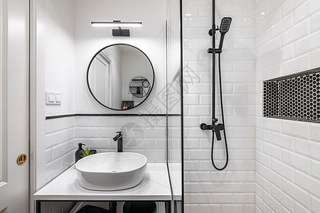 黑白风格的现代浴室配有优质昂贵的配件 白色砖墙和台面上的水槽与镶有镜框和装饰元素的黑色水龙头相得益彰图片