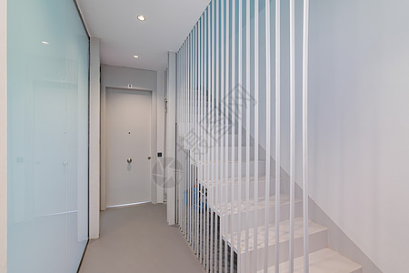 在一栋现代建筑中 通往二楼的白色楼梯带有柔和的蓝色灯光 独创的落地围栏设计方案 由金属白杆制成 具有失重的效果图片