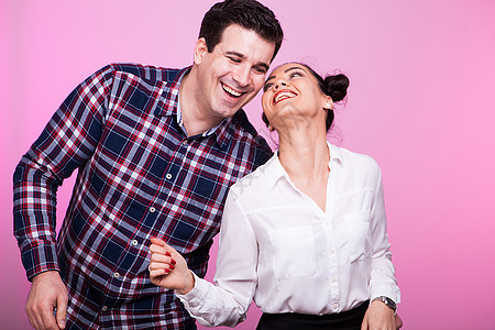 粉红背景的一对在工作室里笑的情侣图片