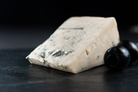 法国奶酪 羊乳干酪 盘子里放着橄榄 特写 深色背景中带橄榄的法式羊乳干酪 发霉的奶酪和橄榄 黑色背景上的蓝纹奶酪牛奶饮食奶制品草图片