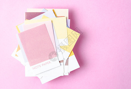 您的文字或信件在粉色颜色背景上的彩色空白粘贴笔记纸的最顶端视图图片