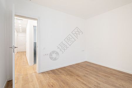 空荡荡的房间铺有复合地板 新粉刷的白墙位于经过翻新的公寓内 走廊通往其他房间 维修和施工概念压板装修硬木石膏房子建筑空白地板地面图片