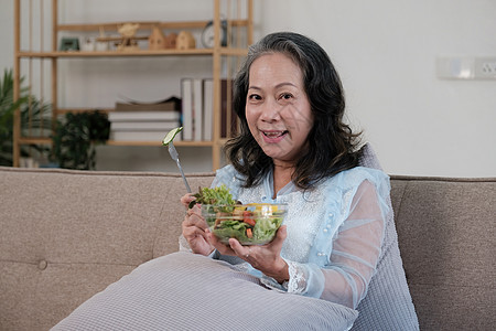享受新鲜绿色沙拉的年老女性快乐 高龄女性在家里身体健康 锻炼和健康的饮食概念成人桌子厨房家庭男人水果老年微笑女士烹饪图片