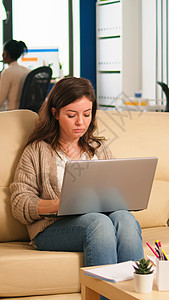 雇员在休息区用可舒适沙发打字 使用笔记本电脑图片