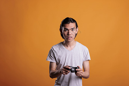年青的亚洲人玩电脑电子游戏 用棍棒打图片