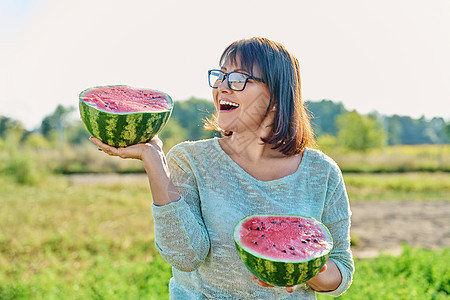 露天手握着一半成熟西瓜的笑女人农场农业采摘生态水果收成女性种植园工作园丁图片